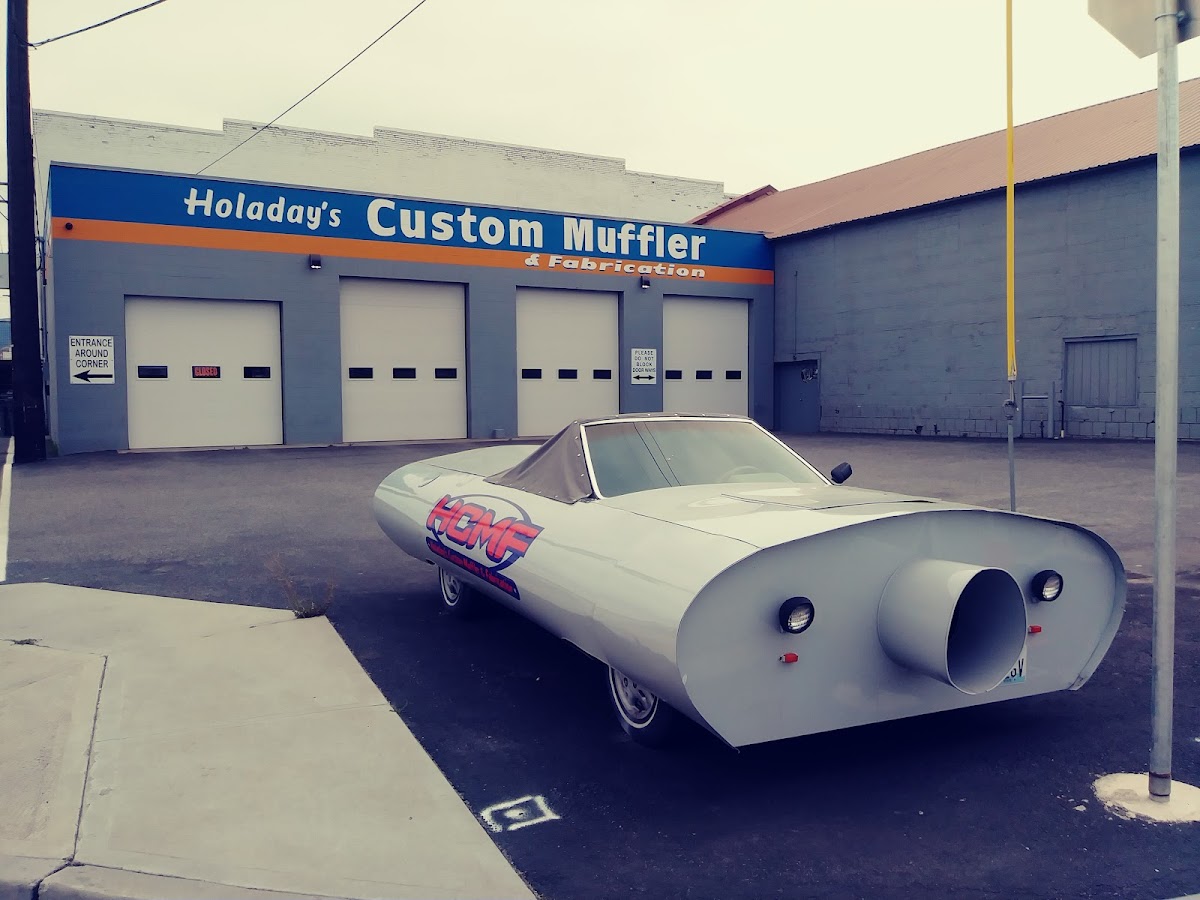 Holaday's Custom Muffler & Fabrication storefront with the HCMF muffler car out front